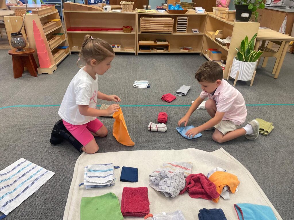kids folding towels in a Montessori classroom