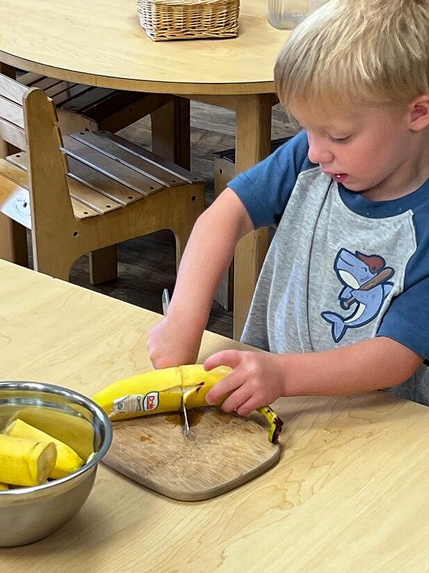student preparing food in a Montessori classroom