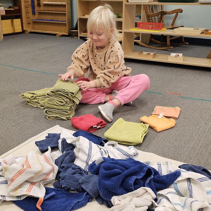 child folding towels as a practical life activity in a montessori classroom