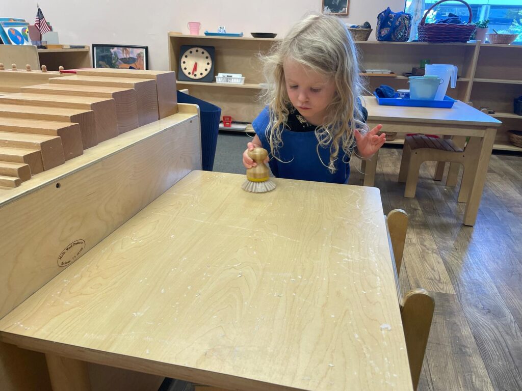 child cleaning a table at a Montessori school