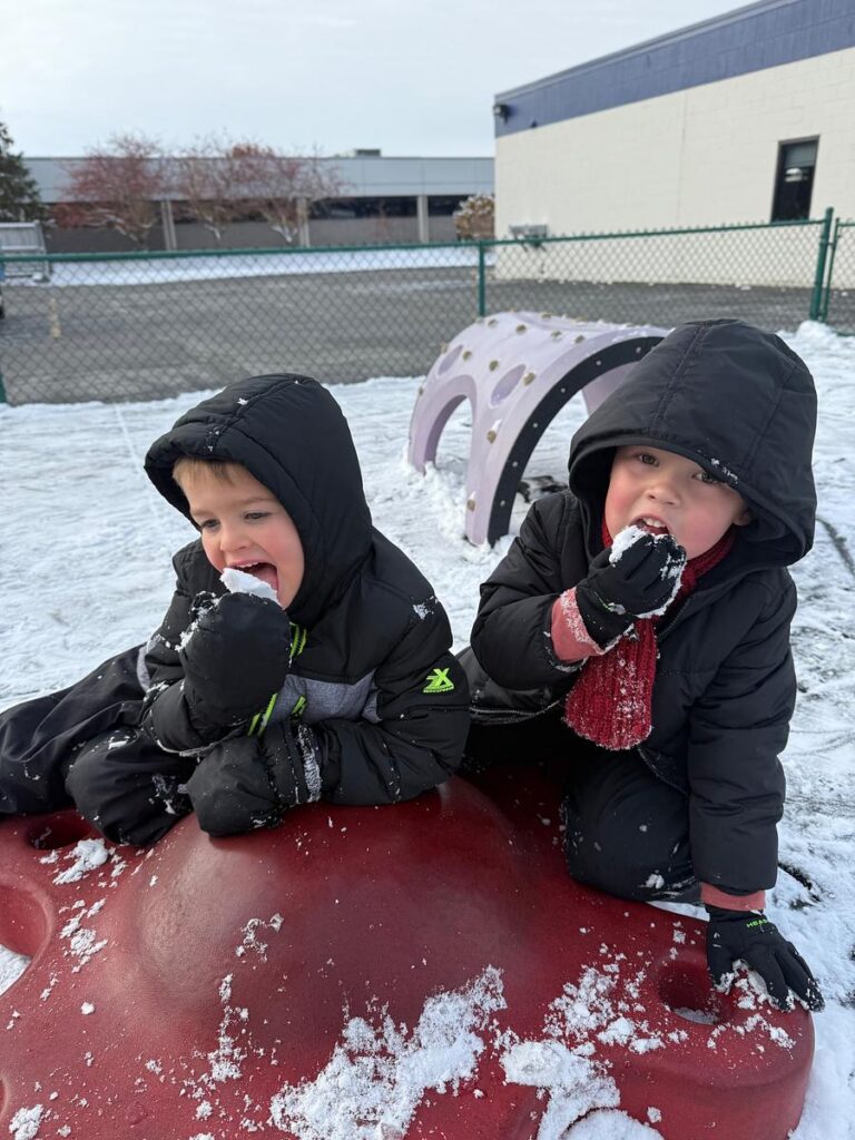 Children eating snow outside during playtime at a Montessori school in Fort Wayne, IN
