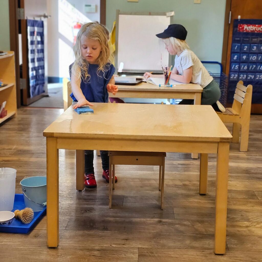 child cleaning a table at a Montessori school