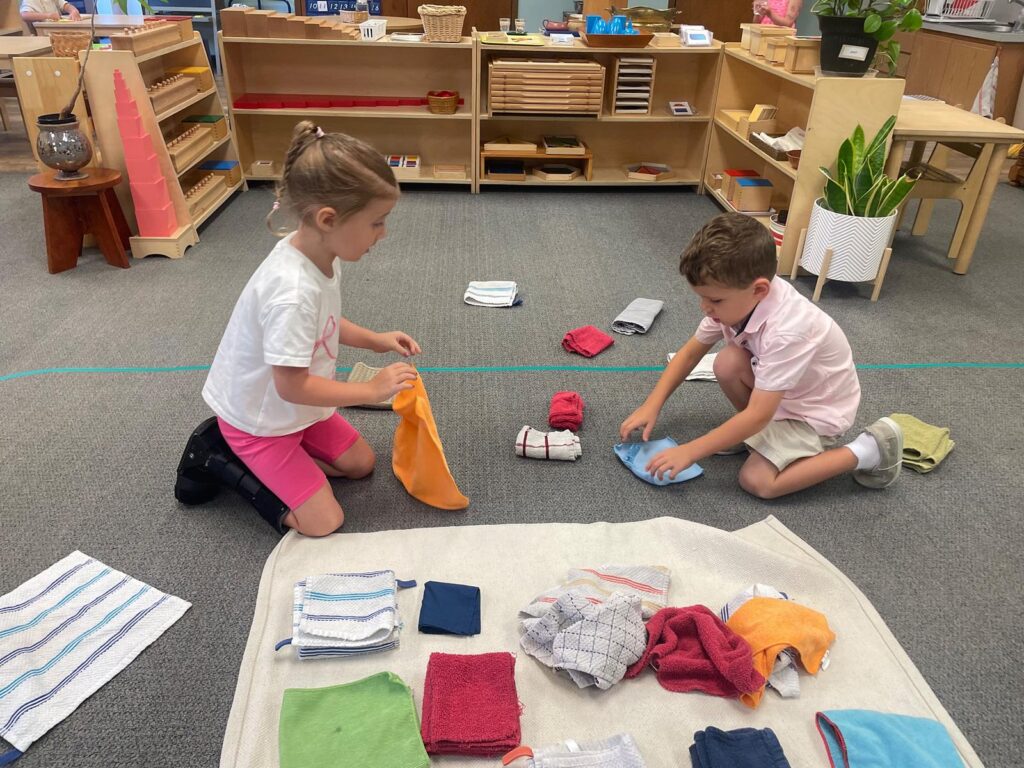kids folding towels in a Montessori classroom
