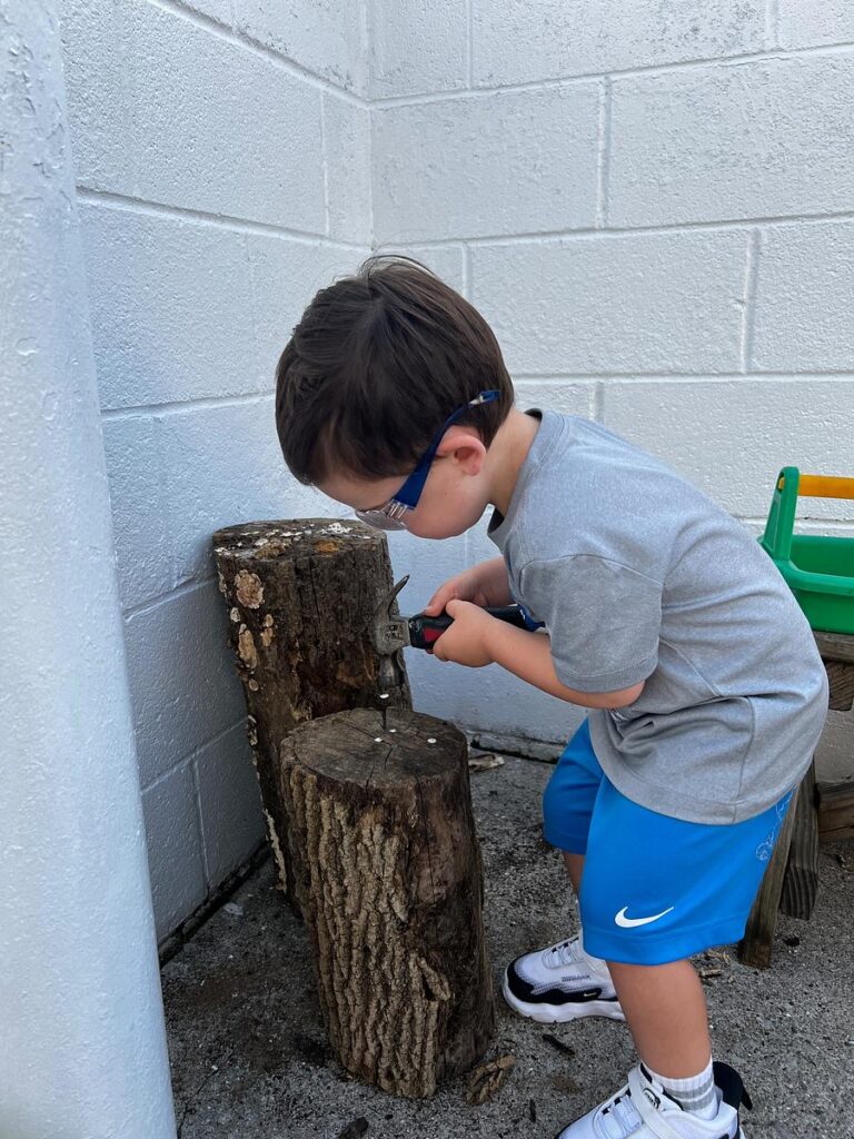 child using a real hammer and nail at a Montessori school