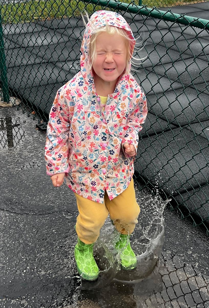 student splashing in a puddle at a Montessori school