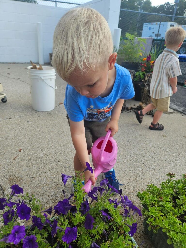 child watering flowers at a Montessori school